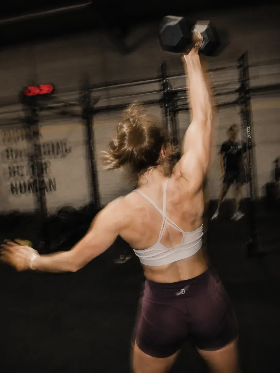 Una atleta levanta una mancuerna sobre la cabeza en un box